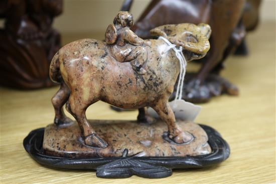 Three Chinese figural wood carvings and a soapstone carving of a child riding a water buffalo,